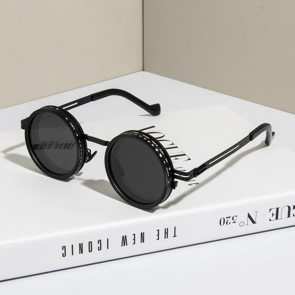 Black polarized round sunglasses with adjustable dimming resting on a white box.