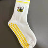 Weiße Strick-Yoga-Socken mit gelbem Zierrand und schwarzem Bienenmotiv.
