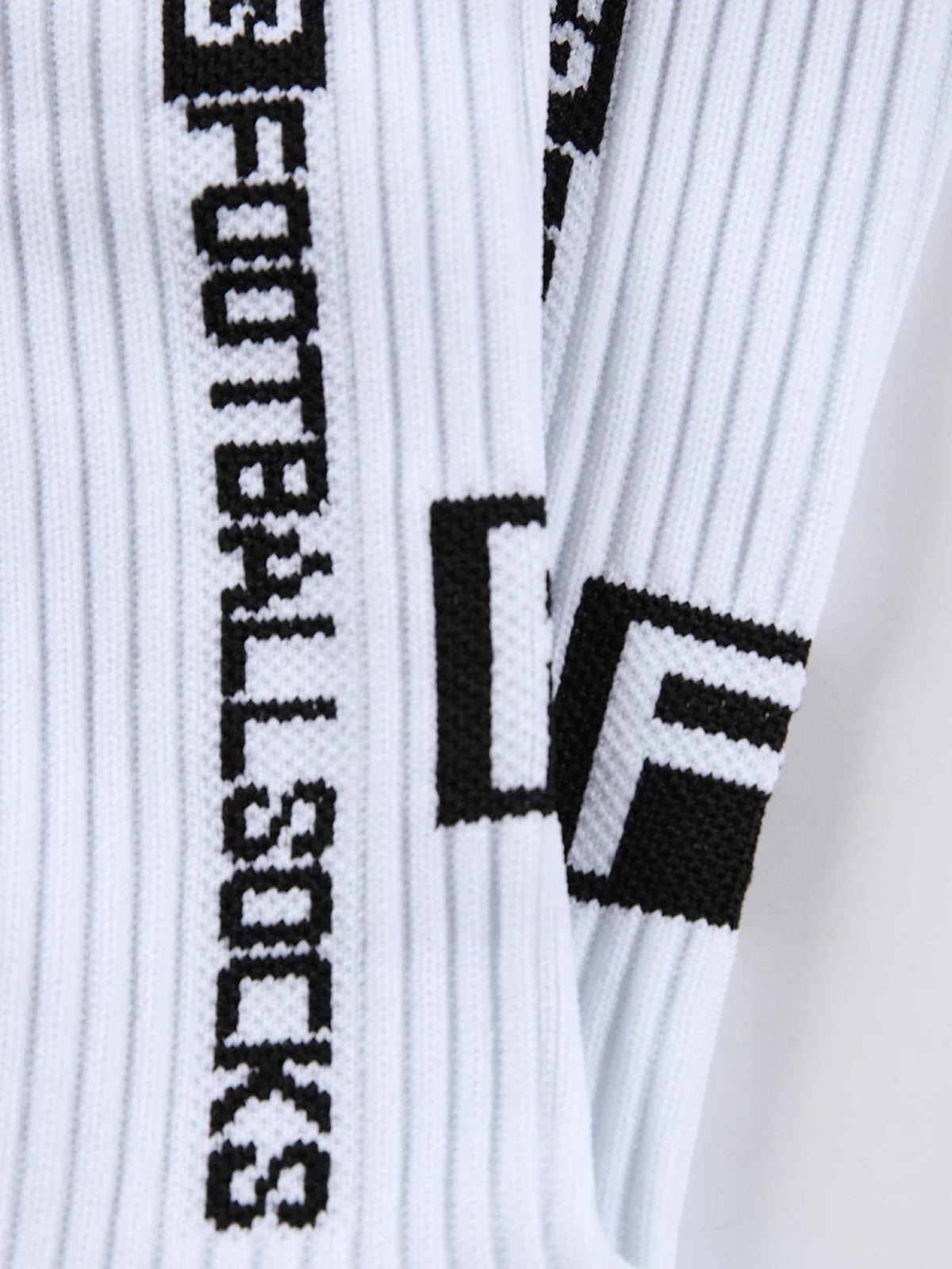 Close-up of white and black athletic soccer socks with a vertical striped pattern and a black logo detail.