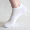 Weiße sportliche Knöchelsocken auf dem Fuß eines Models, von der Seite gezeigt.