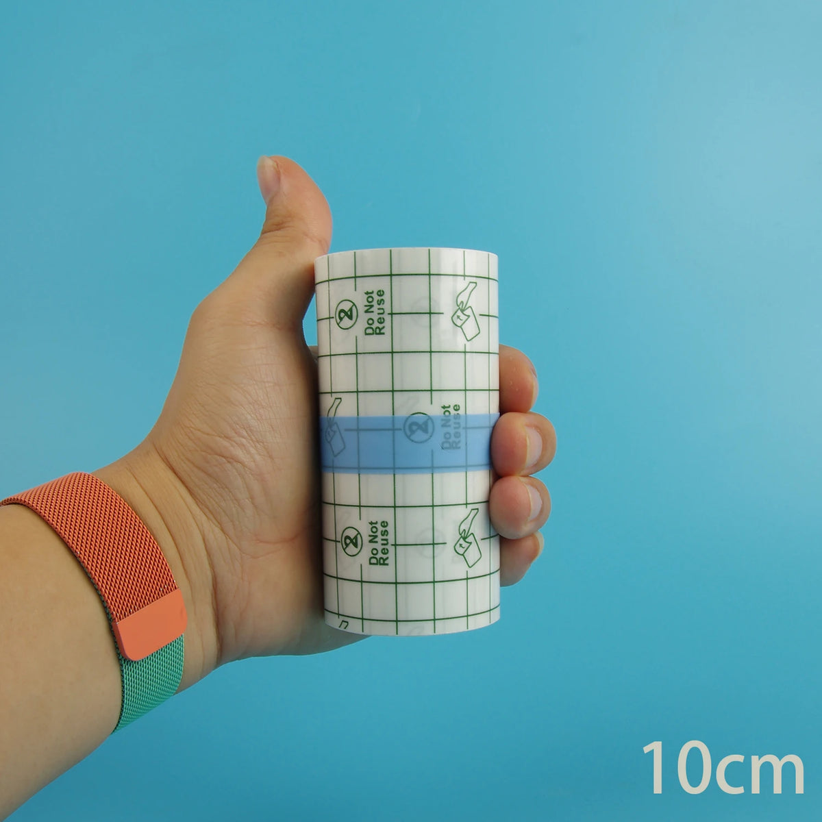 Eine Hand hält eine Rolle wasserfeste Tattoo-Heilfolie mit Warnhinweis vor blauem Hintergrund.
