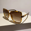 A pair of retro two-tone gradient sunglasses with tortoiseshell frames and brown lenses resting on a white surface.