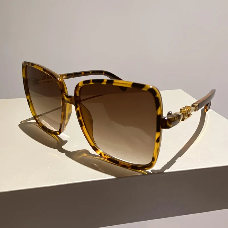 A pair of retro two-tone gradient sunglasses with tortoiseshell frames and brown lenses resting on a white surface.