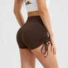 A model wears dark brown performance yoga shorts with a drawstring waist and a white top.