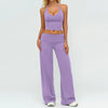 A woman wearing a purple women's premium fitness tracksuit consisting of a cropped top and long pants.