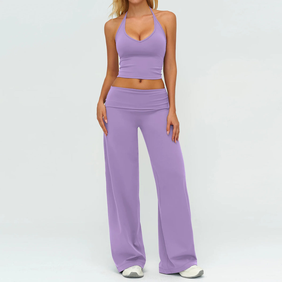 A woman wearing a purple women's premium fitness tracksuit consisting of a cropped top and long pants.