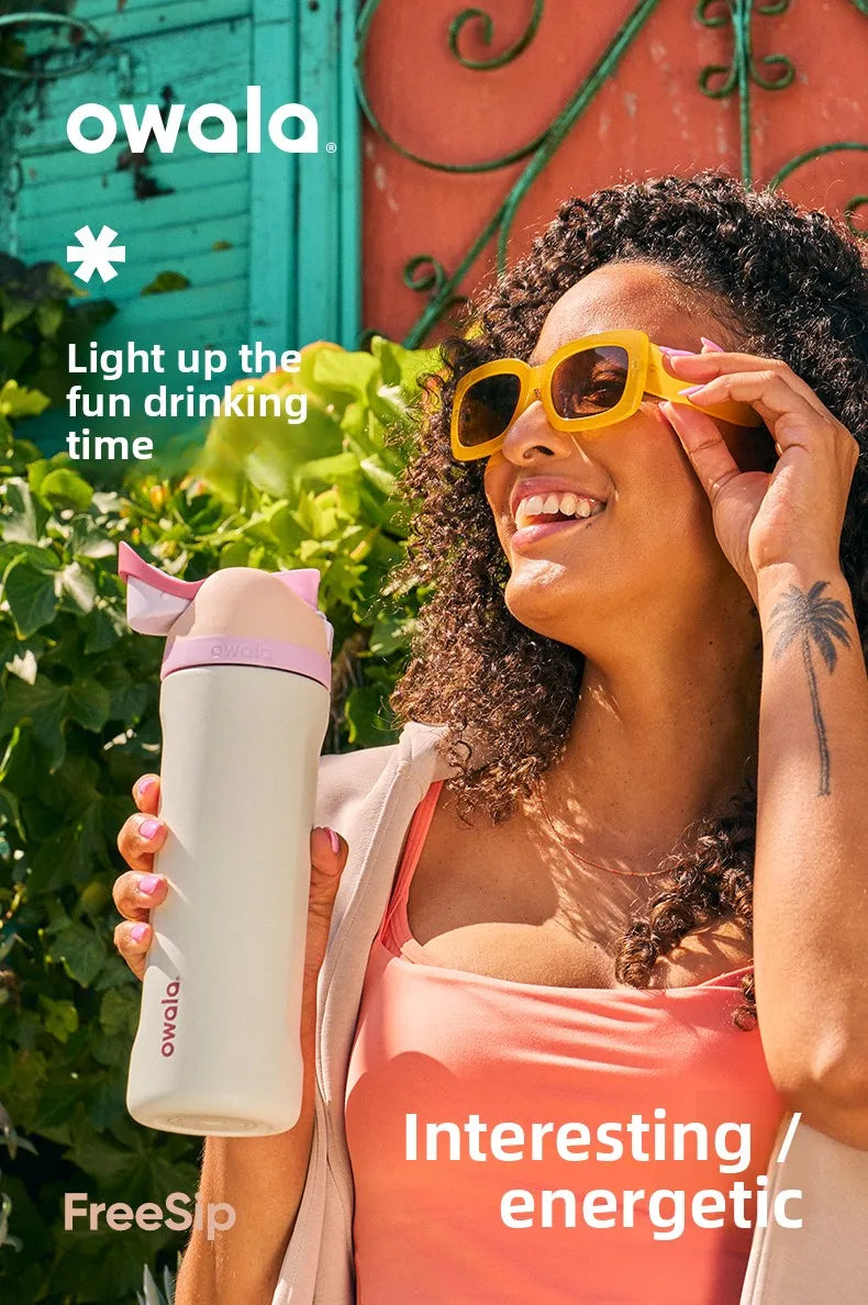 Eine Frau hält eine Owala isolierte Wasserflasche im Freien und lächelt, trägt eine Sonnenbrille.