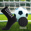 Black non-slip athletic socks with outer grips shown next to a soccer ball on a green field.