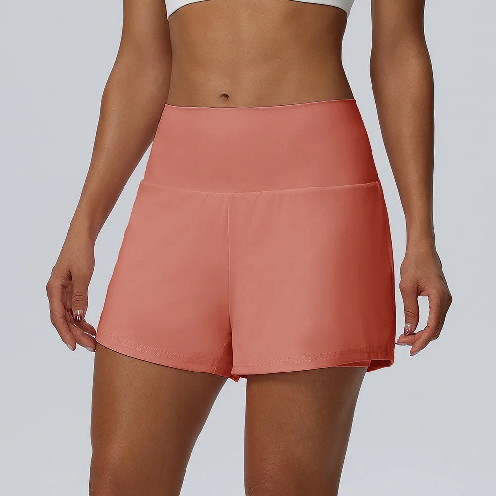 Eine Frau trägt korallrosa schnelltrocknende Sportshorts.