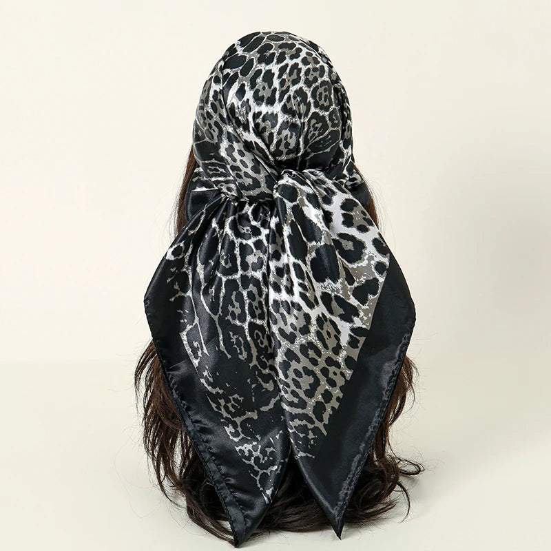 A black and gray leopard print satin square scarf tied around dark hair.