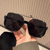 A hand holds a pair of black UV400 double beam sunglasses against a light background.