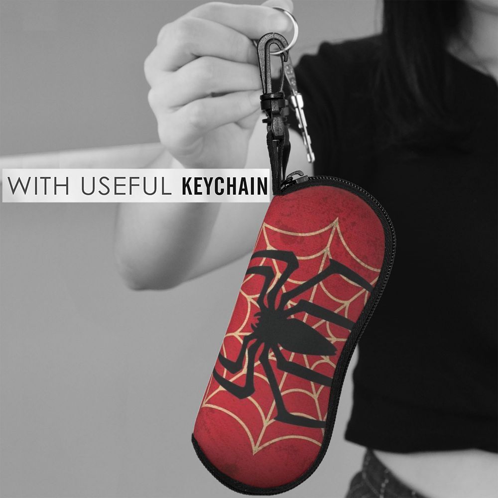 A hand holds a red spider web shaped keychain pouch with a black spider design.