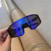 A hand holds a pair of blue-tinted cycling sunglasses against a light background.