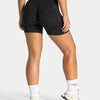A woman wearing black leopard print seamless yoga shorts and white socks and sneakers.