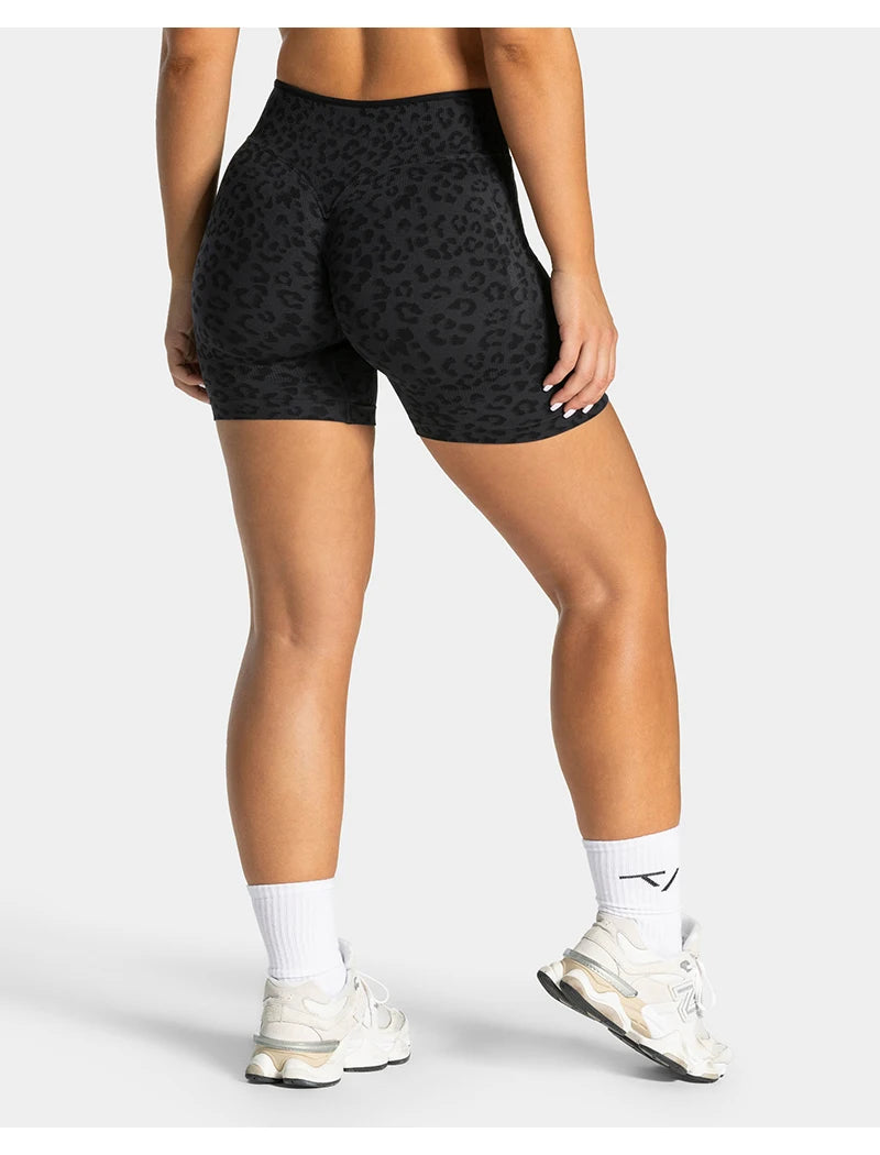A woman wearing black leopard print seamless yoga shorts and white socks and sneakers.