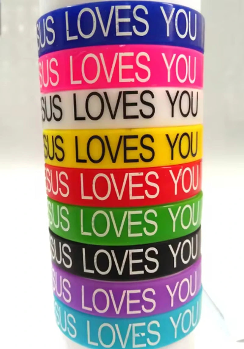 A stack of colorful silicone religious cuff bracelets in various shades including blue, pink, black, yellow, red, green, and 