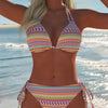 A woman wearing an elegant two-piece swimsuit set with colorful geometric patterns by the ocean.