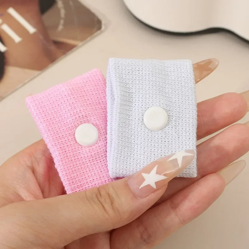 A hand holds two white and pink knitted wristbands for anti-nausea relief.