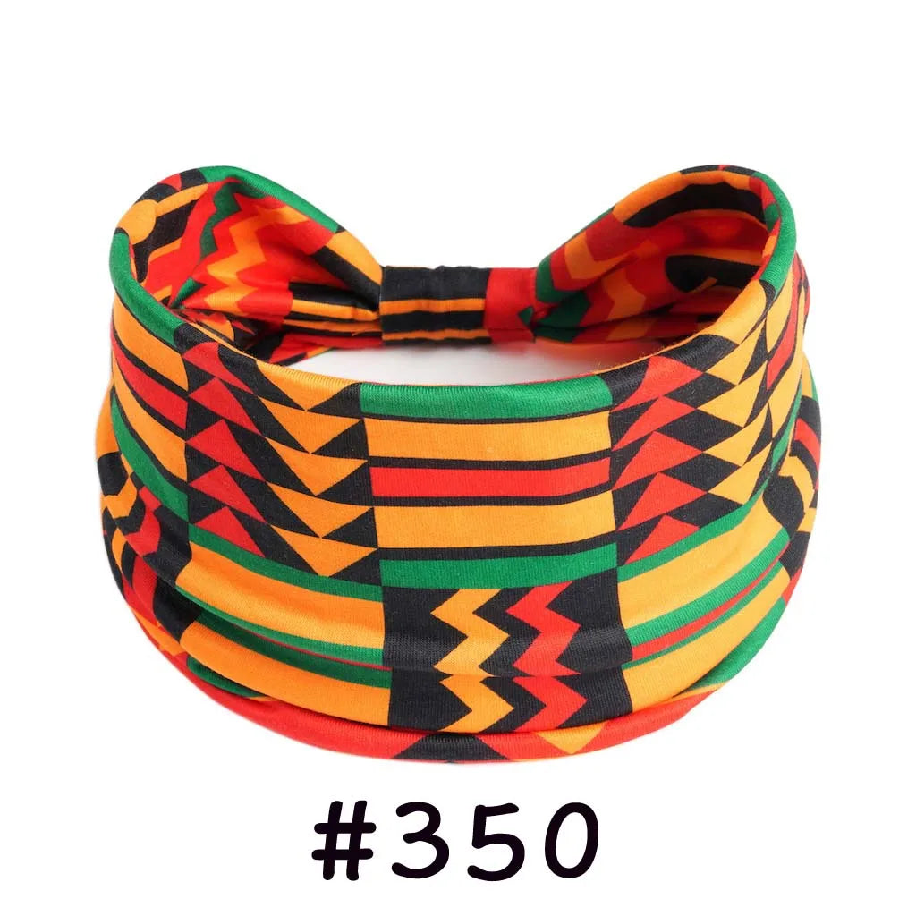 A colorful, patterned boho knotted cotton headband featuring geometric designs in orange, red, green, and black.