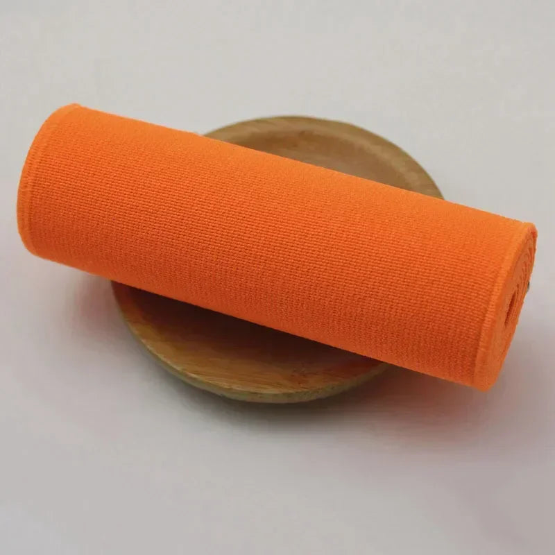 A bright orange elastic band rolled up, resting on a wooden surface.