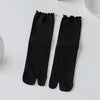Black knit crew socks with ruffle cuffs displayed on a white surface.