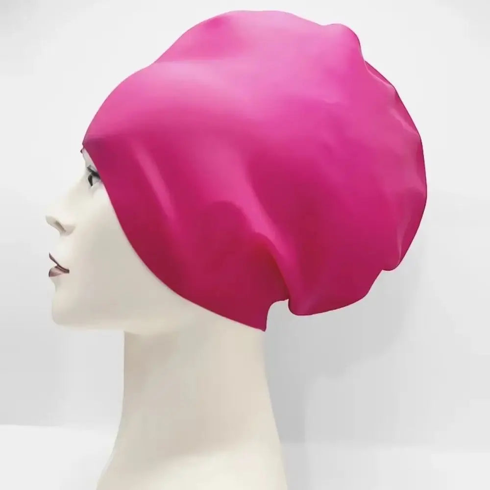 A magenta silicone swim cap is displayed on a mannequin head.