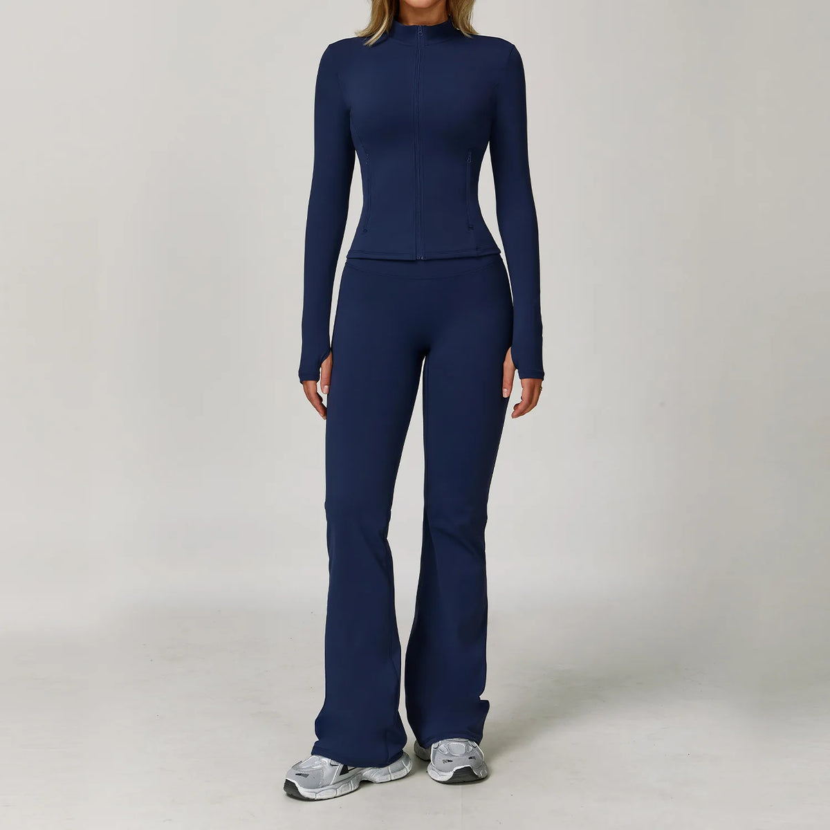 A woman wearing a navy blue 3-piece yoga sports set consisting of a long-sleeved top and matching pants.