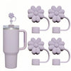 A purple silicone straw cover for a tumbler and several flower-shaped silicone covers.