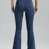 A model wearing dark blue high-waisted bootcut yoga pants and a matching sports bra.