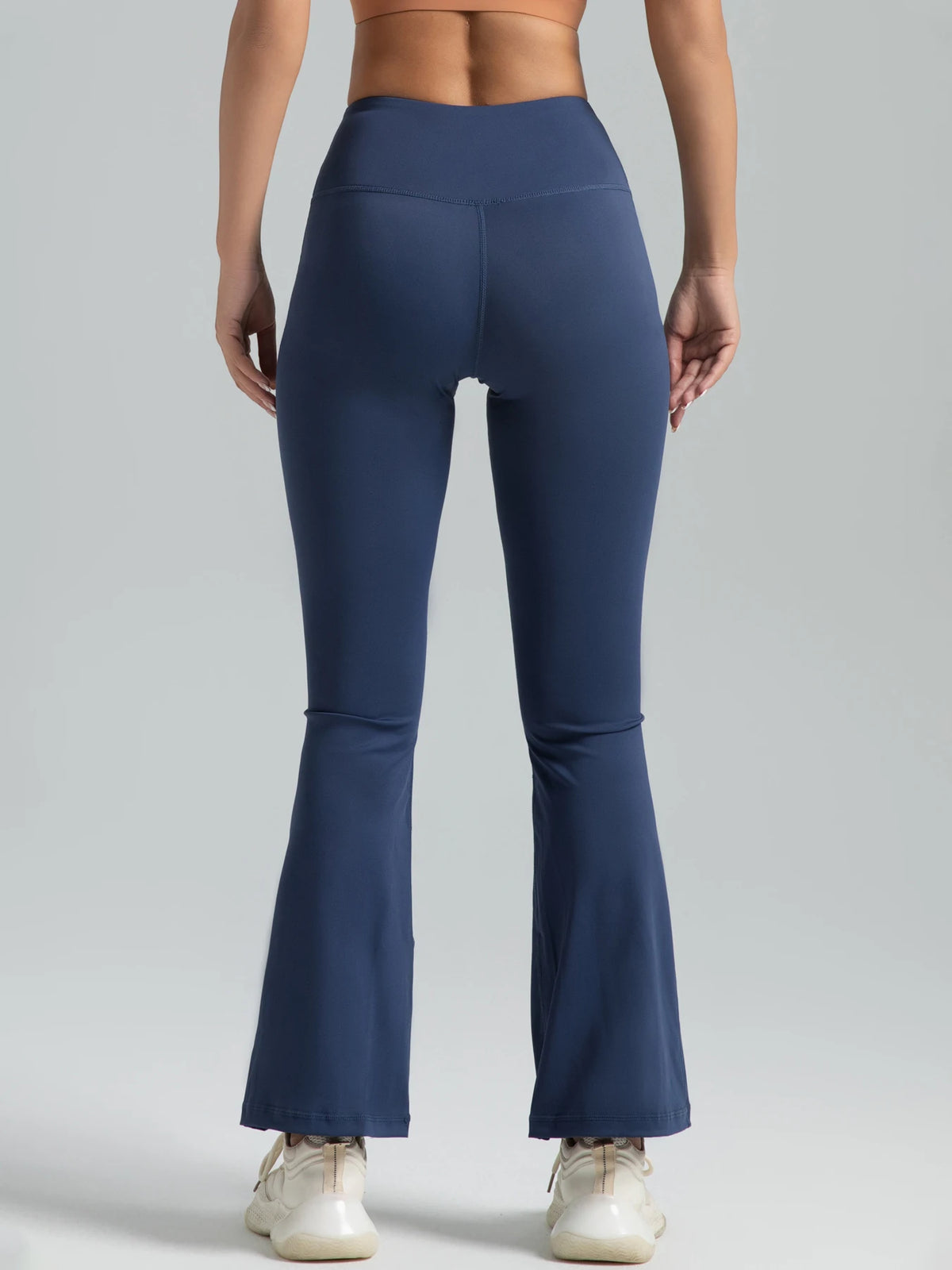 A model wearing dark blue high-waisted bootcut yoga pants and a matching sports bra.