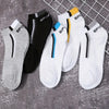 A collection of men's color-block mesh ankle socks in gray, black, white, and yellow are displayed on a wire rack.