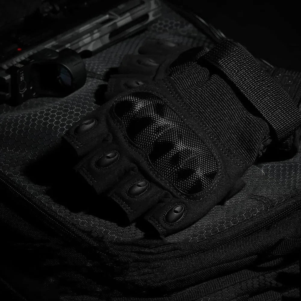 A close-up view of black tactical fingerless gloves resting on a dark fabric background.