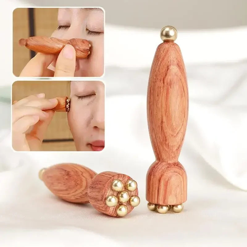 A wooden massage stick with a brass lotus top and gold accents shown in use.