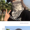 Una mujer vistiendo una gorra de béisbol negra y un pañuelo de cuello blanco con estampado paisley en un entorno al aire libr