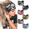 A woman models several floral patterned bohemian cotton stretch headbands in black, blue, and green.