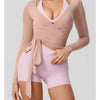 A woman wearing a light pink long sleeve top and matching shorts, posing for a product photo.