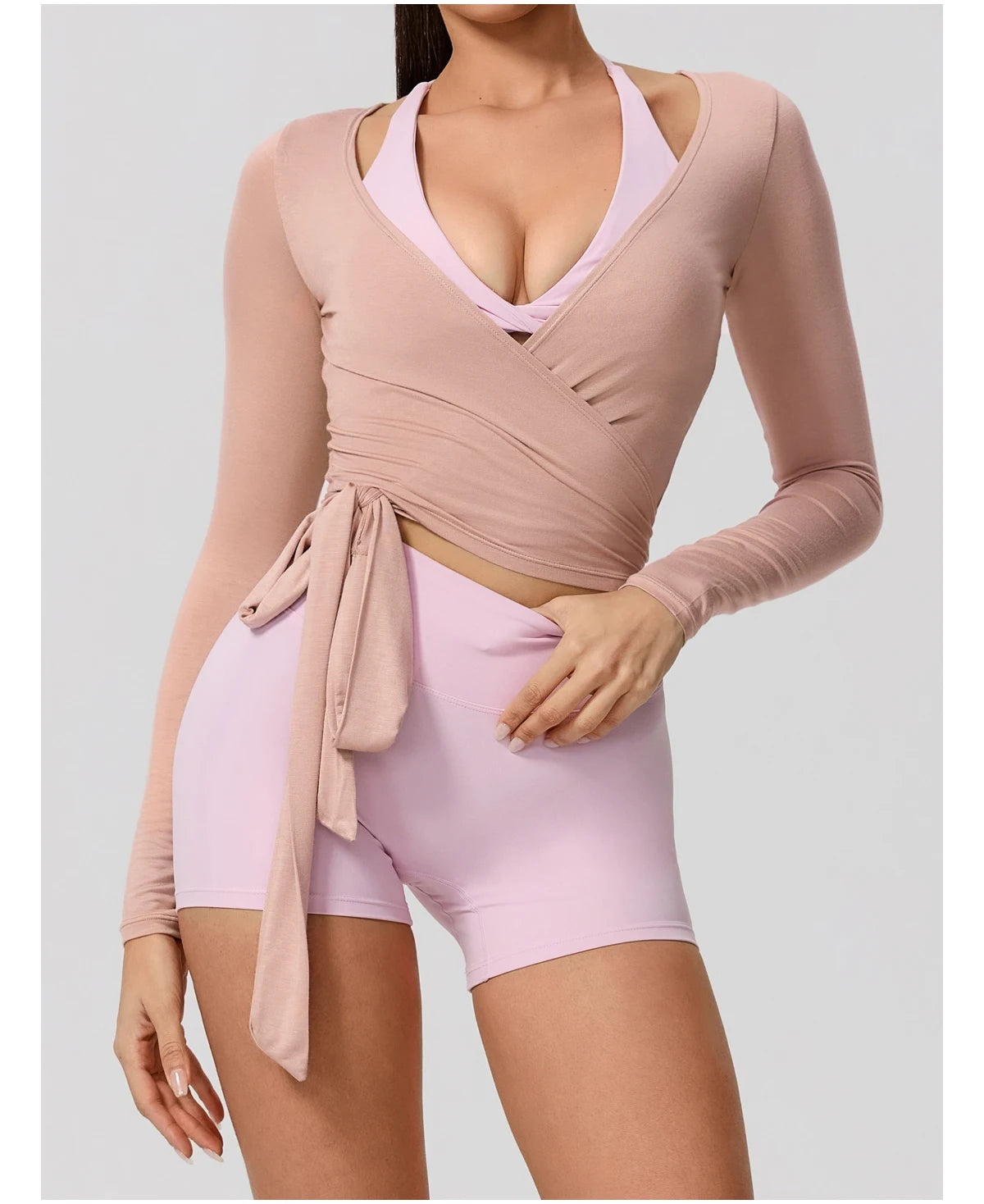 A woman wearing a light pink long sleeve top and matching shorts, posing for a product photo.