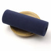 A dark navy elastic band is rolled and resting on a light wood or bamboo plate.
