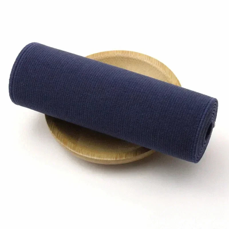 A dark navy elastic band is rolled and resting on a light wood or bamboo plate.