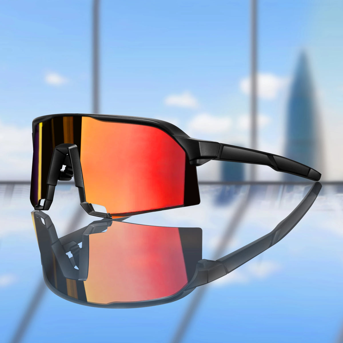 A pair of black cycling sunglasses with vibrant orange and red polarized lenses reflected on a glass surface.