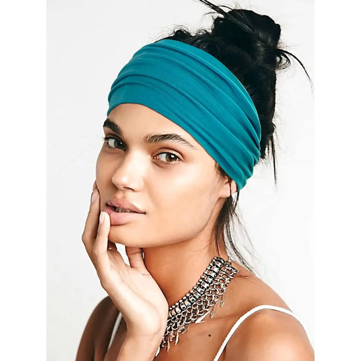 A woman wearing a teal stretch sport headband tied around her hair, looking directly at the camera.
