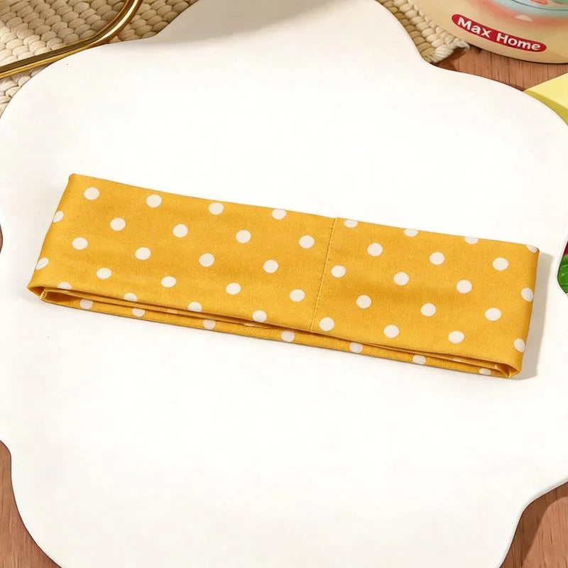 Gelbes Polka-Dot-Stoff-Haarband auf weißer Fläche