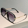 Black and white vintage pilot gradient sunglasses with gold accents resting on a light surface.