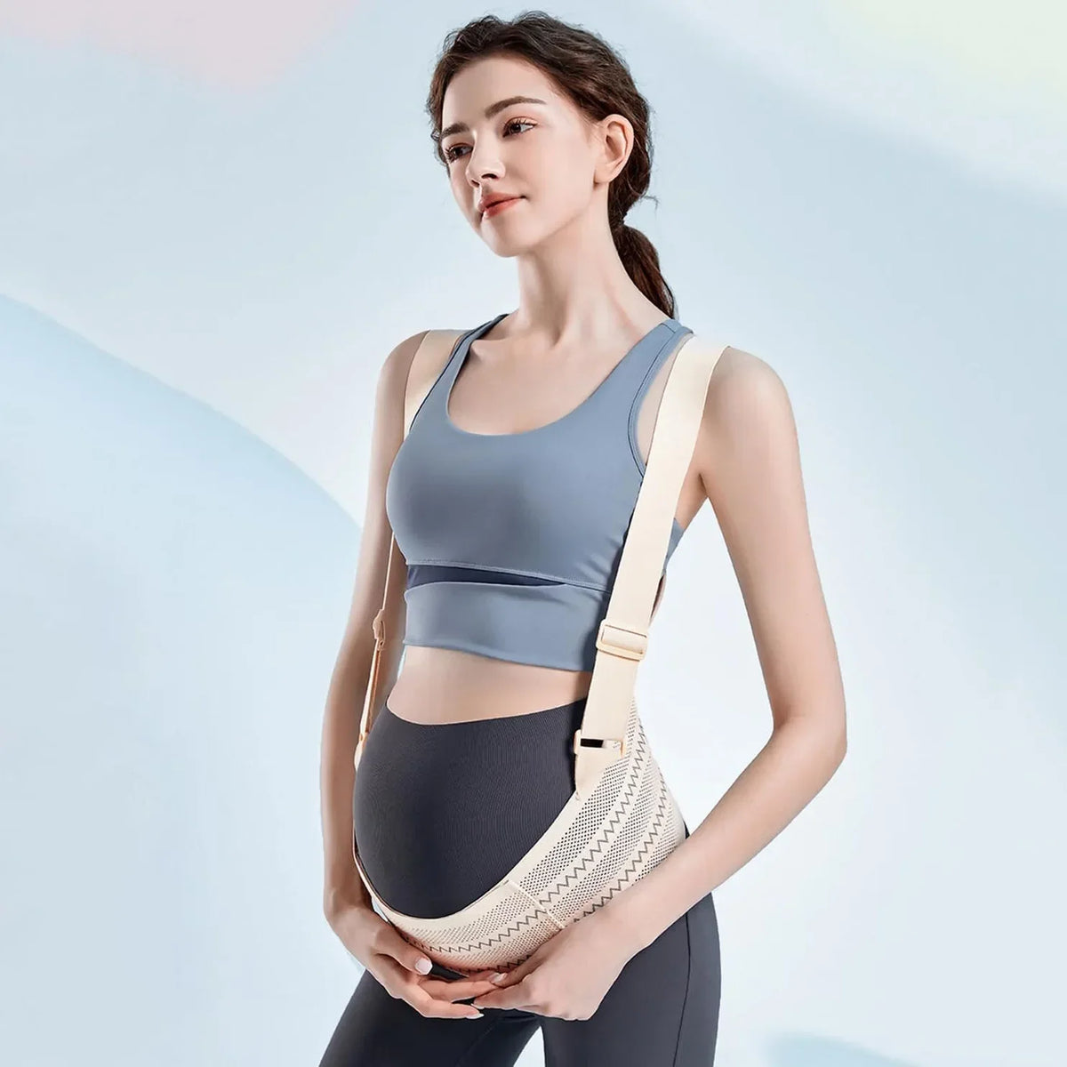 Une femme portant un soutien-ventre beige et des vêtements de sport sombres.