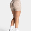 A woman wearing leopard print seamless yoga shorts and white socks, standing against a light background.