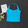 Haut sans bretelles bleu vif pour yoga et fitness, à côté d'une carte blanche et de tulipes roses sur fond gris foncé.