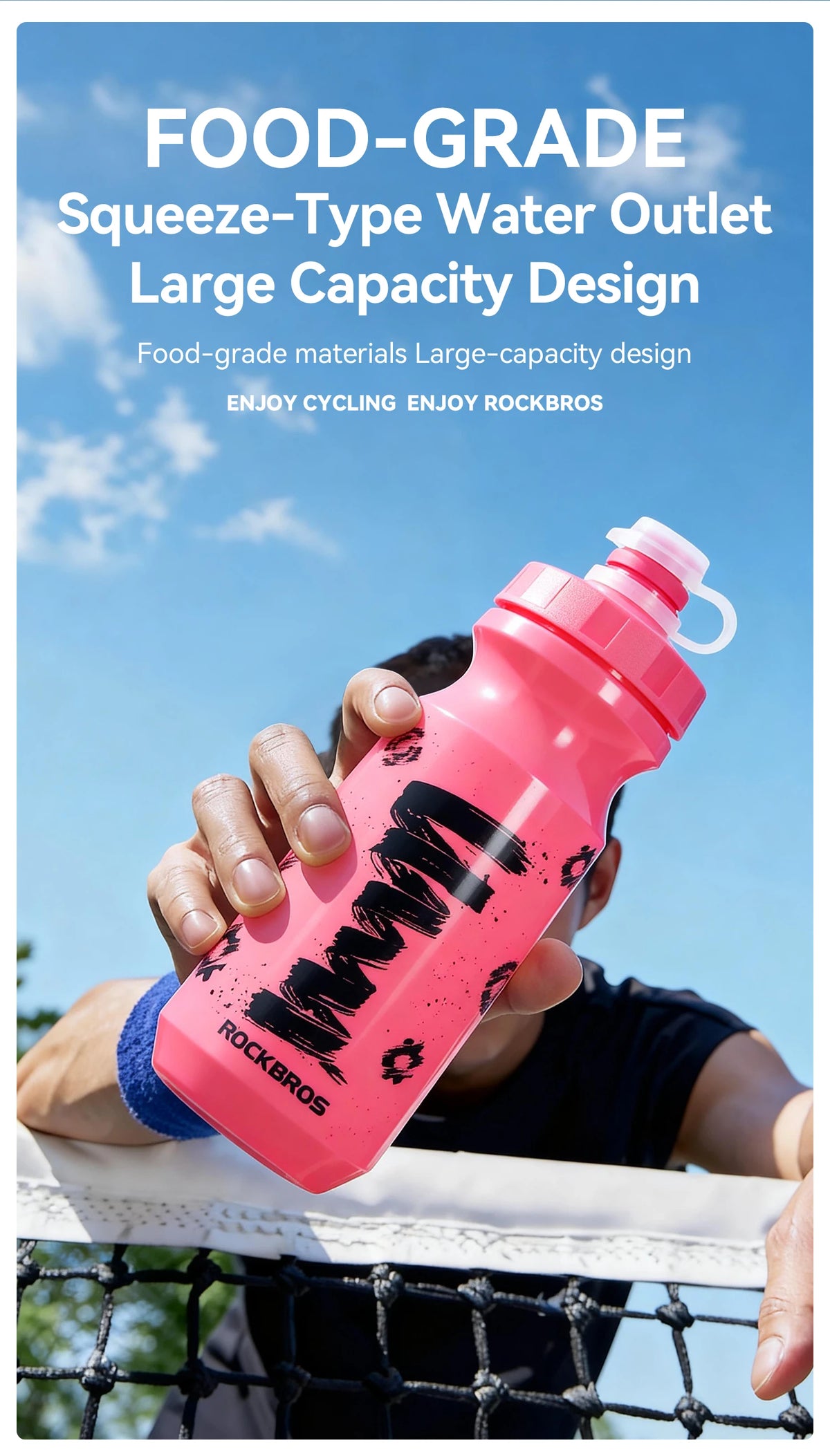 Una mano sostiene una botella de agua tipo exprimidor rosa para ciclismo, con el logo de Rockbros.