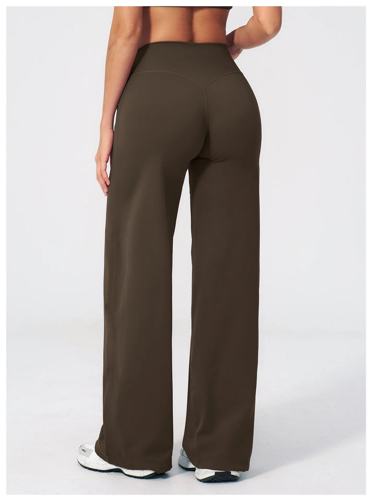 A woman wearing dark brown high-waist flared yoga pants standing in a full-length shot.