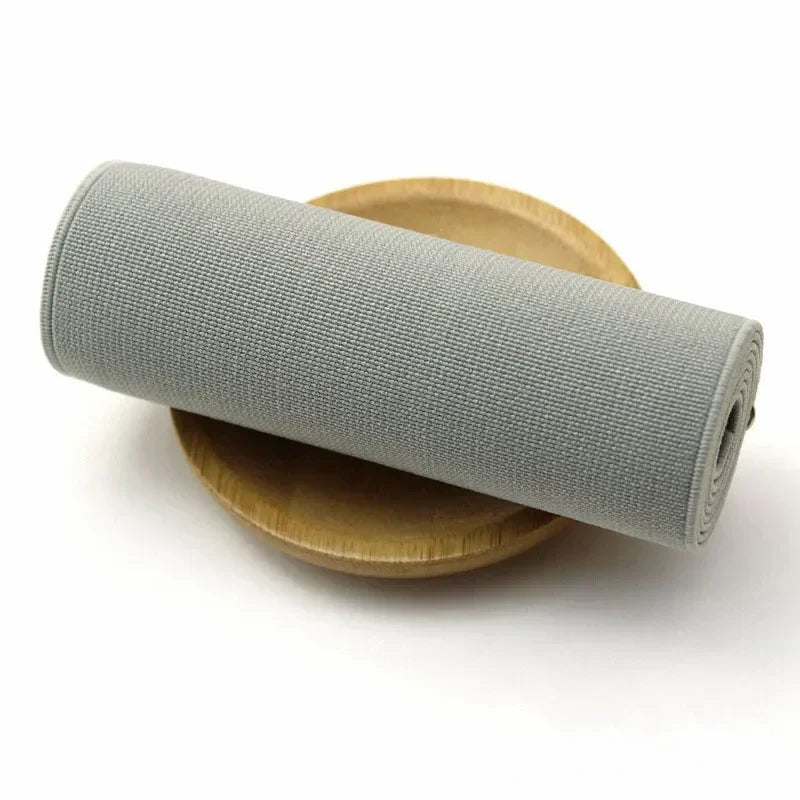 Gray elastic band rolled up on a wooden disk for sewing and decoration