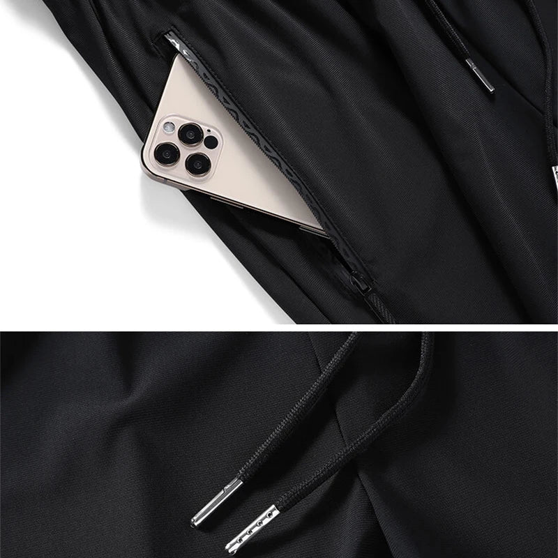 Close-up of a black ice silk performance pant with a white zipper detail and a light-colored smartphone visible.
